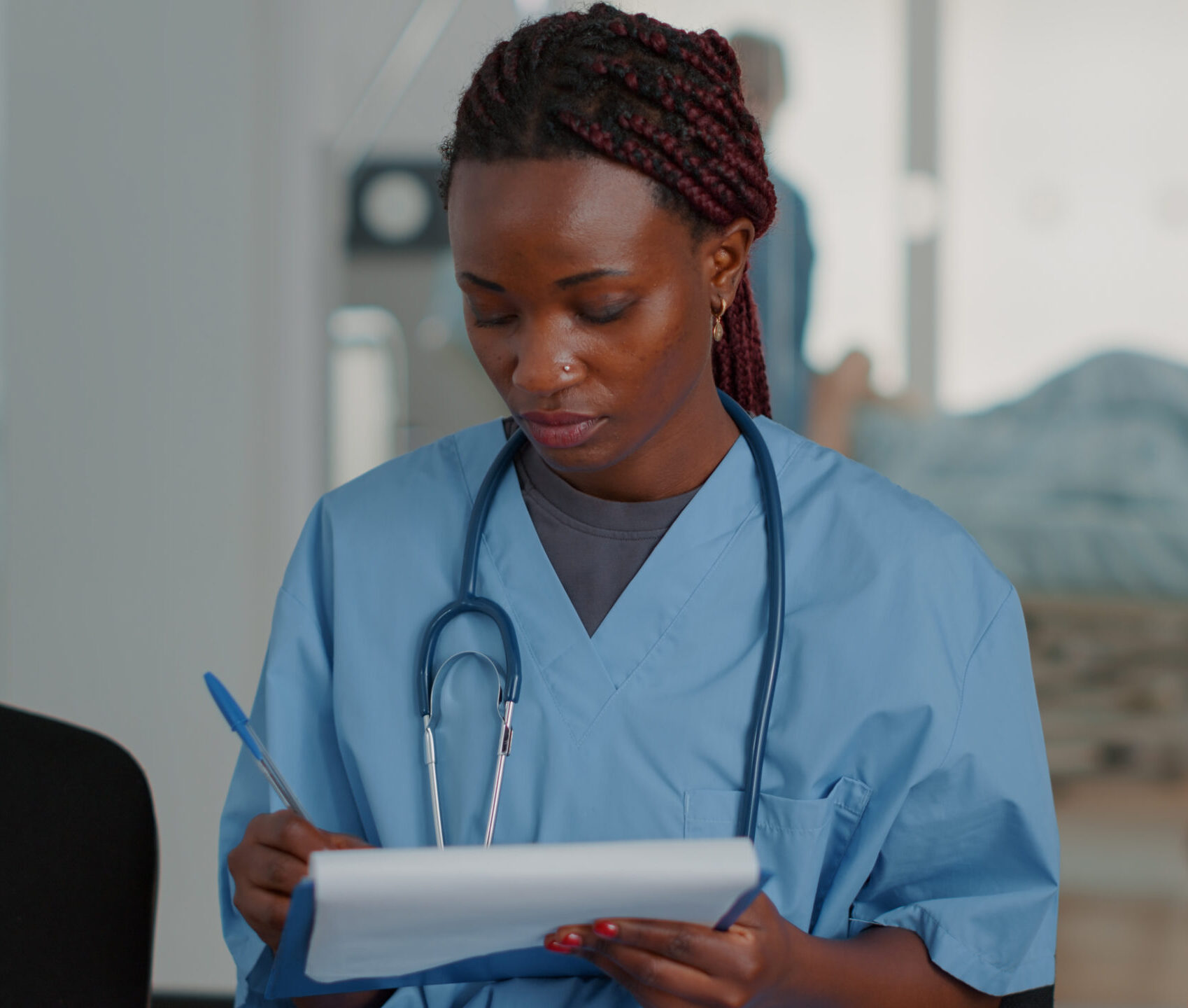 Close up of african american nurse looking at checkup files in waiting room A female nurse writing on a notepad