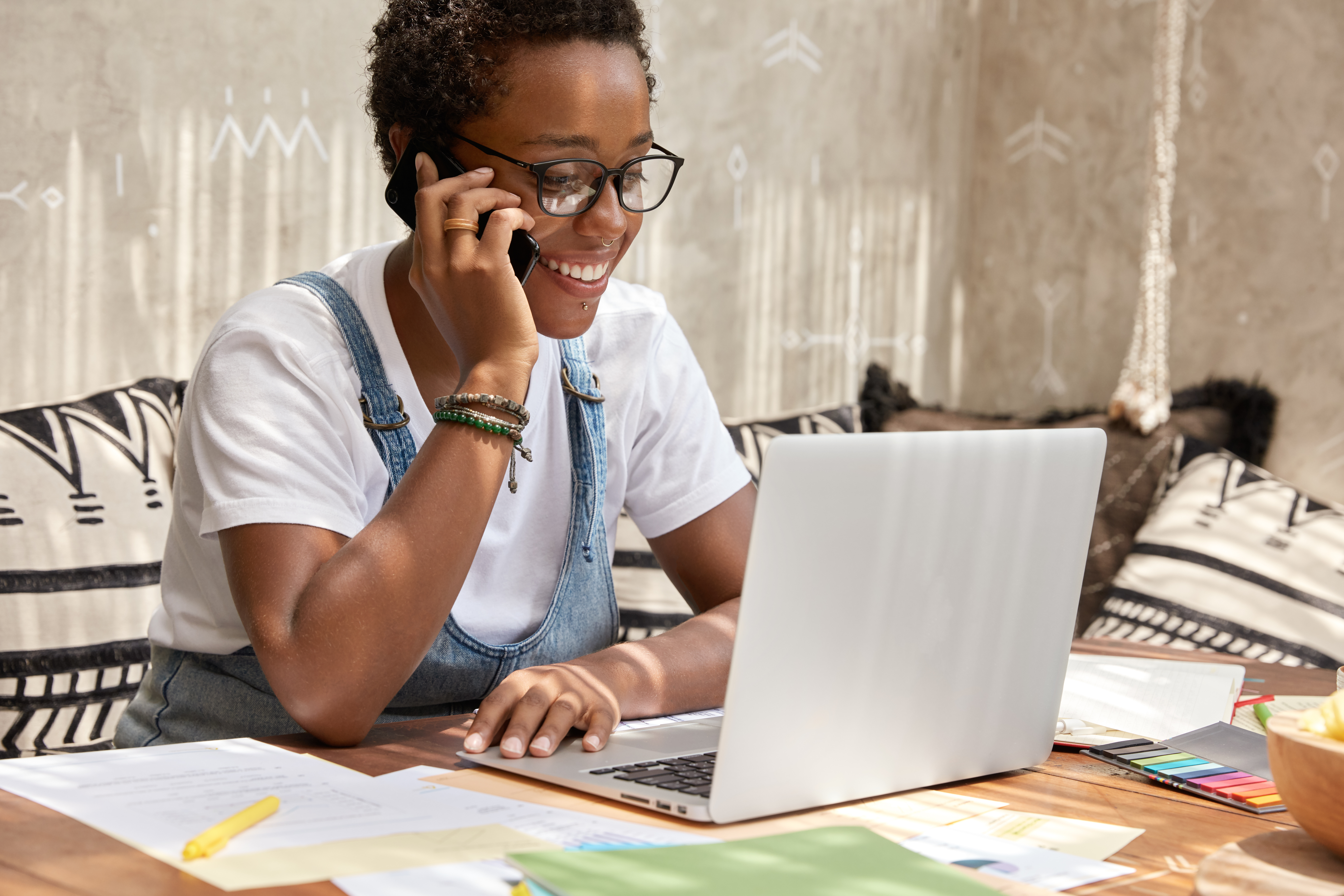 Shot of stylish female recruiter makes job offer, has telephone conversation, connected to high speed internet, checks information in database on laptop computer, pleased to be promoted.