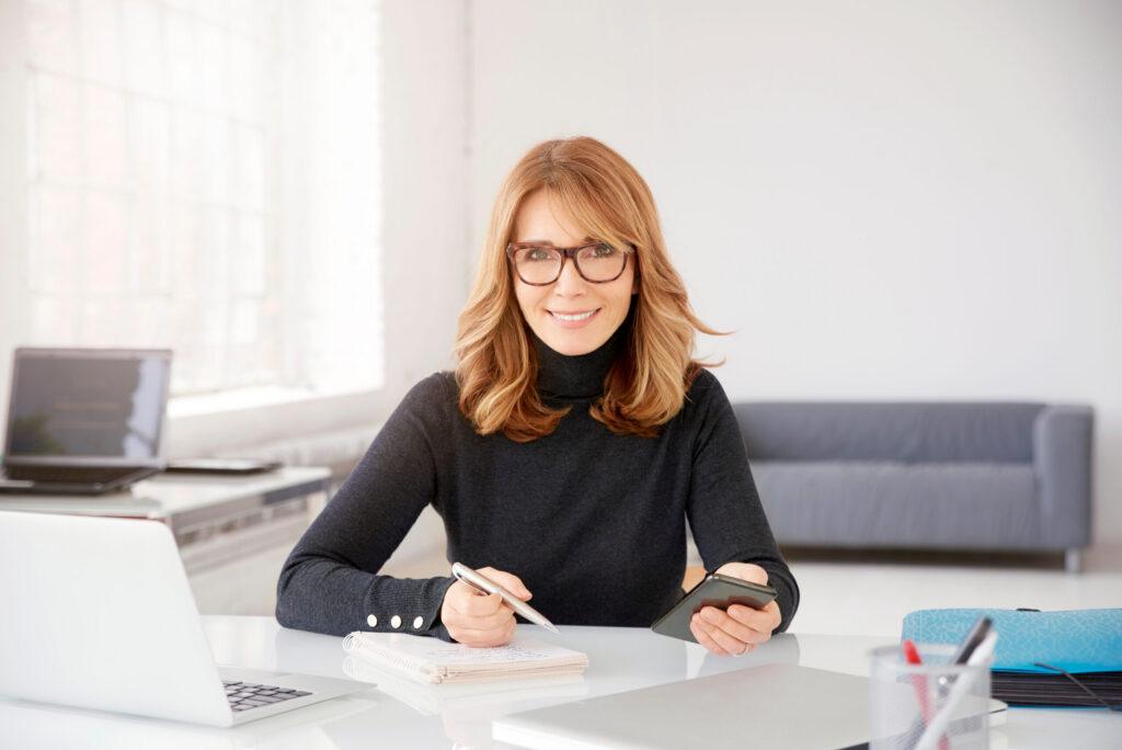 Casual businesswoman text messaging and writing something while