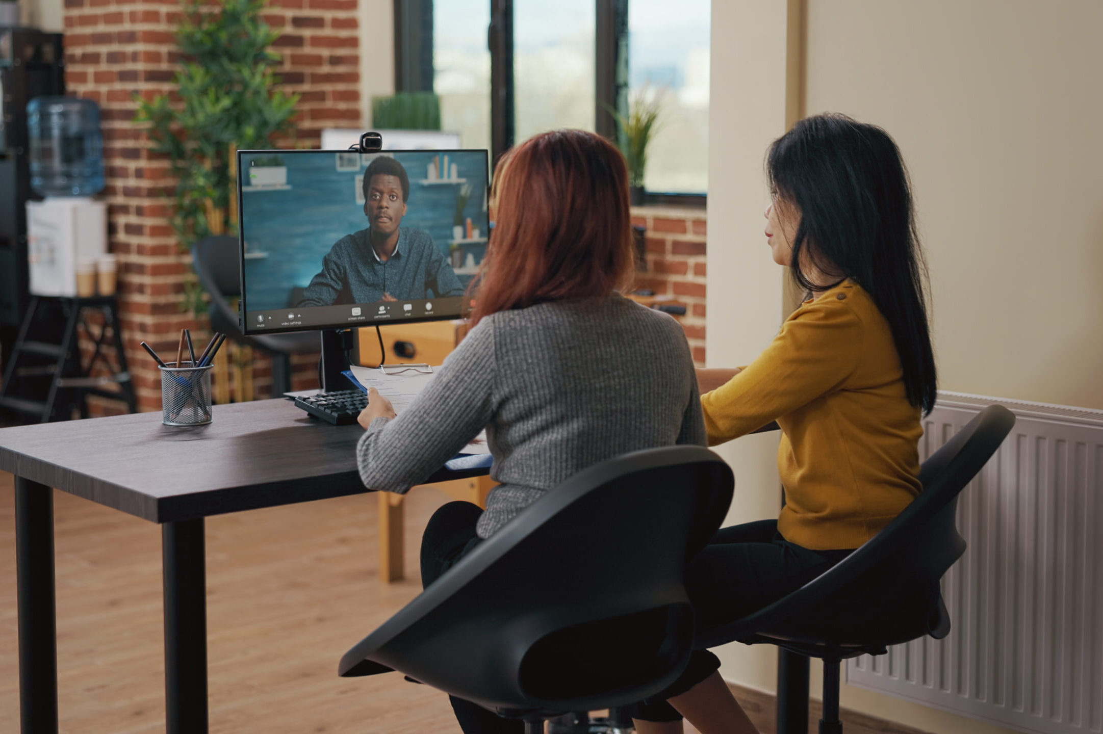 Coworkers using video call on computer to talk to candidate Coworkers using video call on computer to talk to candidate at job interview. Asian women attending remote meeting with applicant on video teleconference to discuss hiring and intern contract.