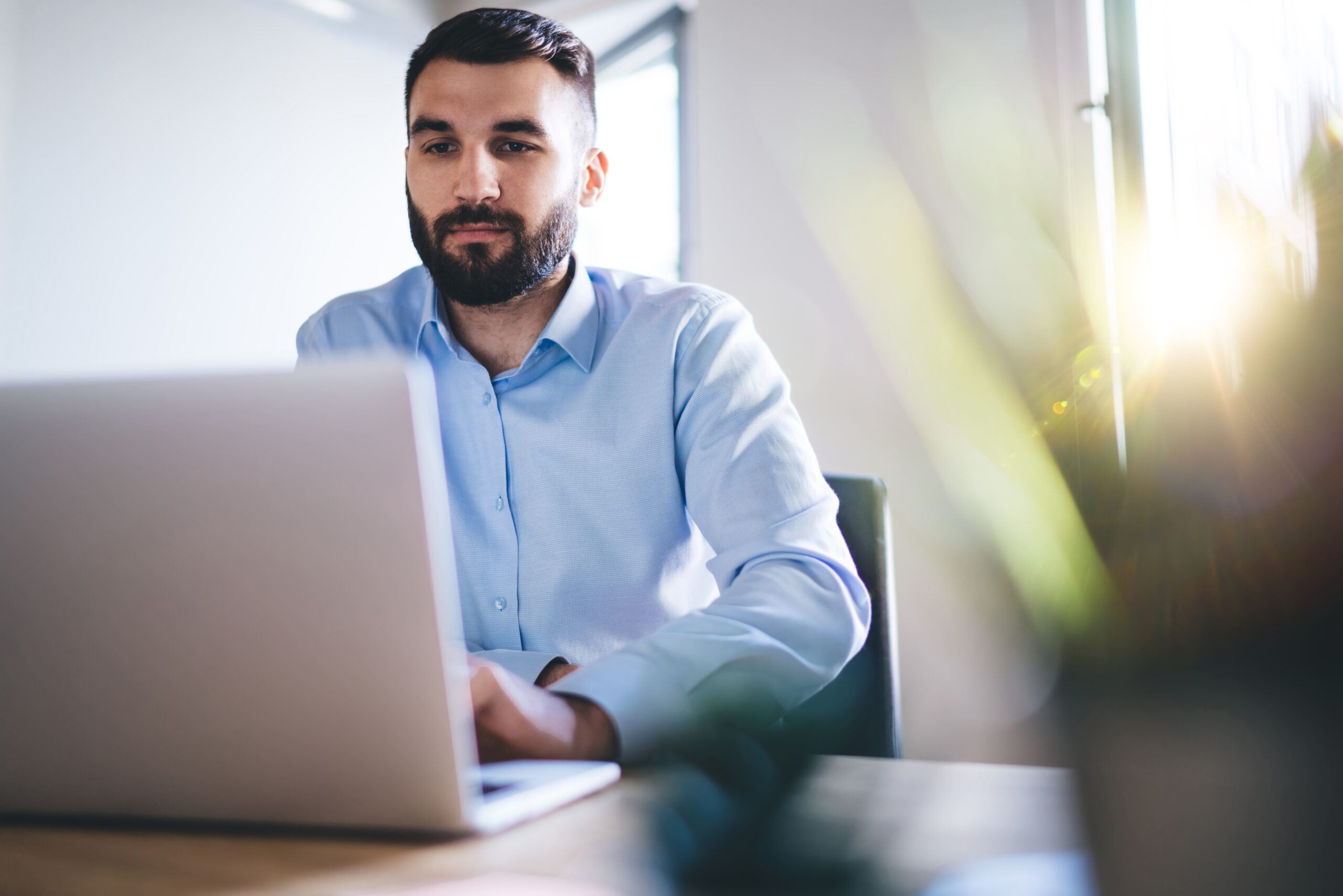 Confident millennial bearded businessman typing on laptop comput