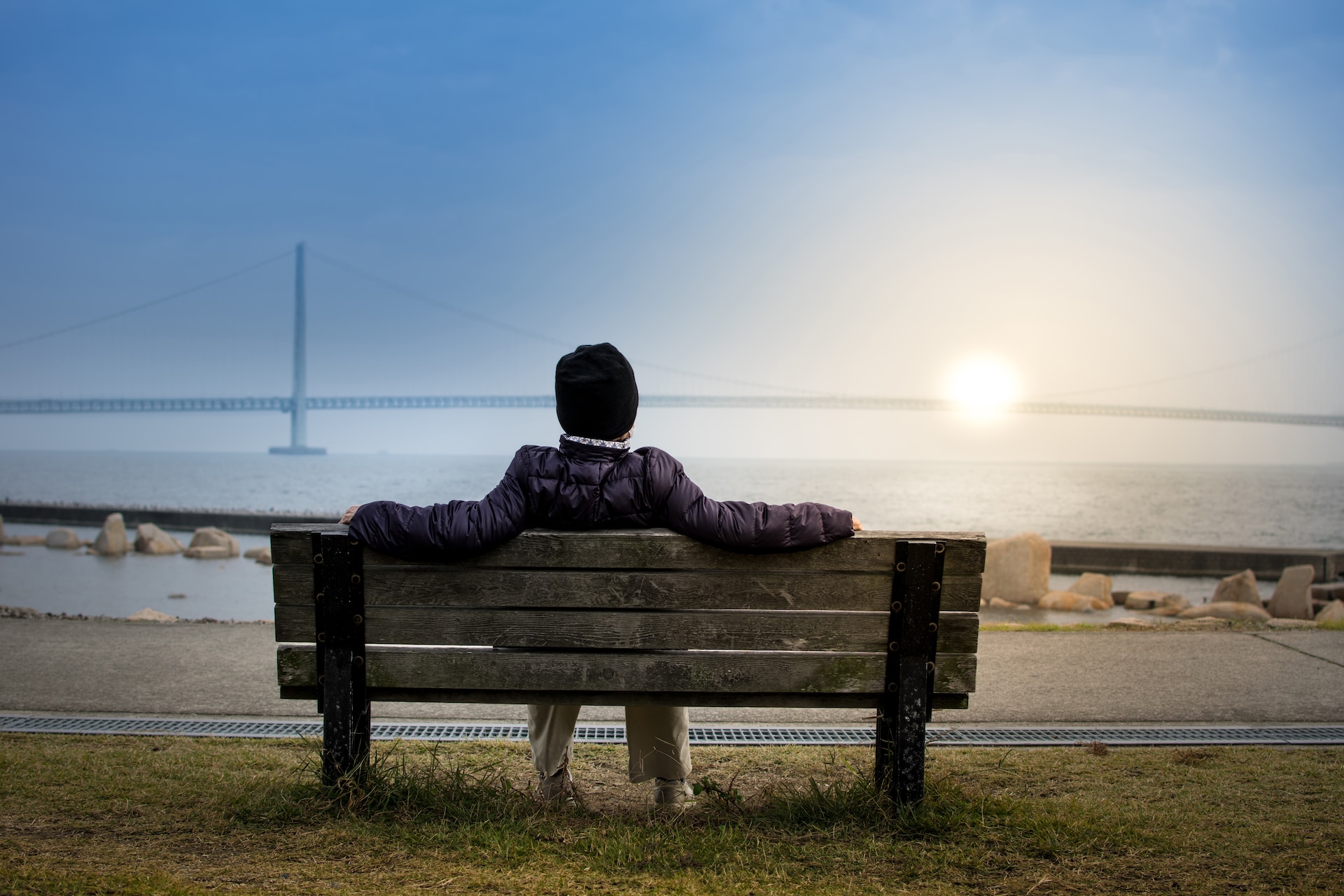 A man resting on a bench during the sunset.