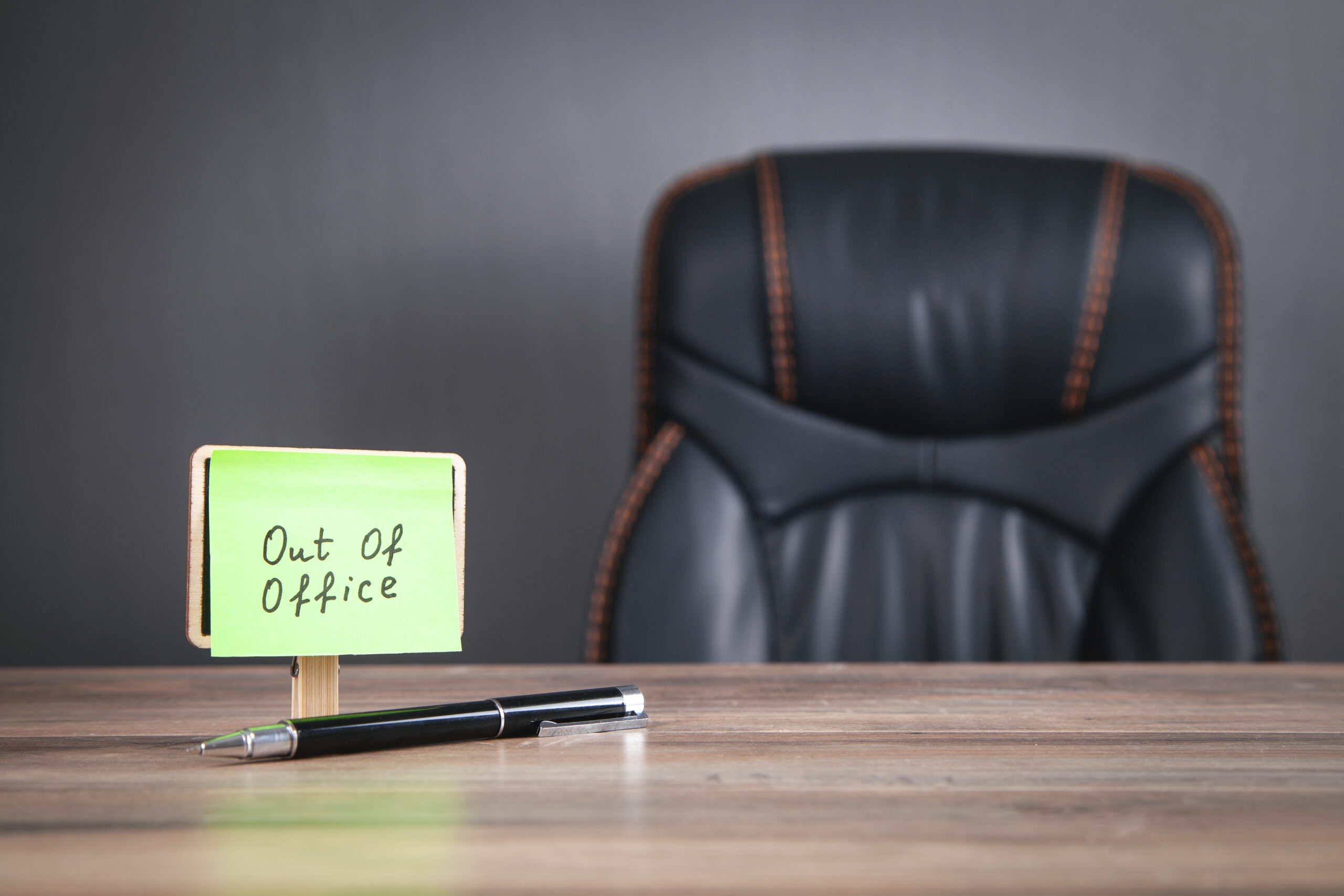 Out of office message on sticky note on the desk.