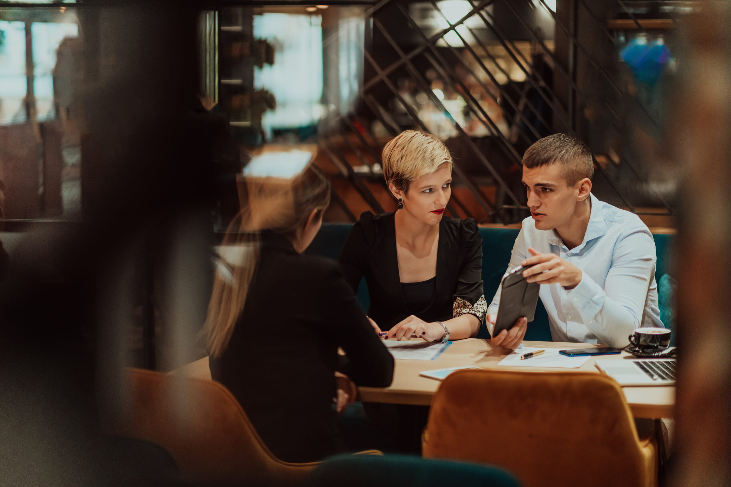 Happy businesspeople smiling cheerfully during a meeting in a coffee shop. Group of successful business professionals working as a team in a multicultural workplace. A group of business people meeting