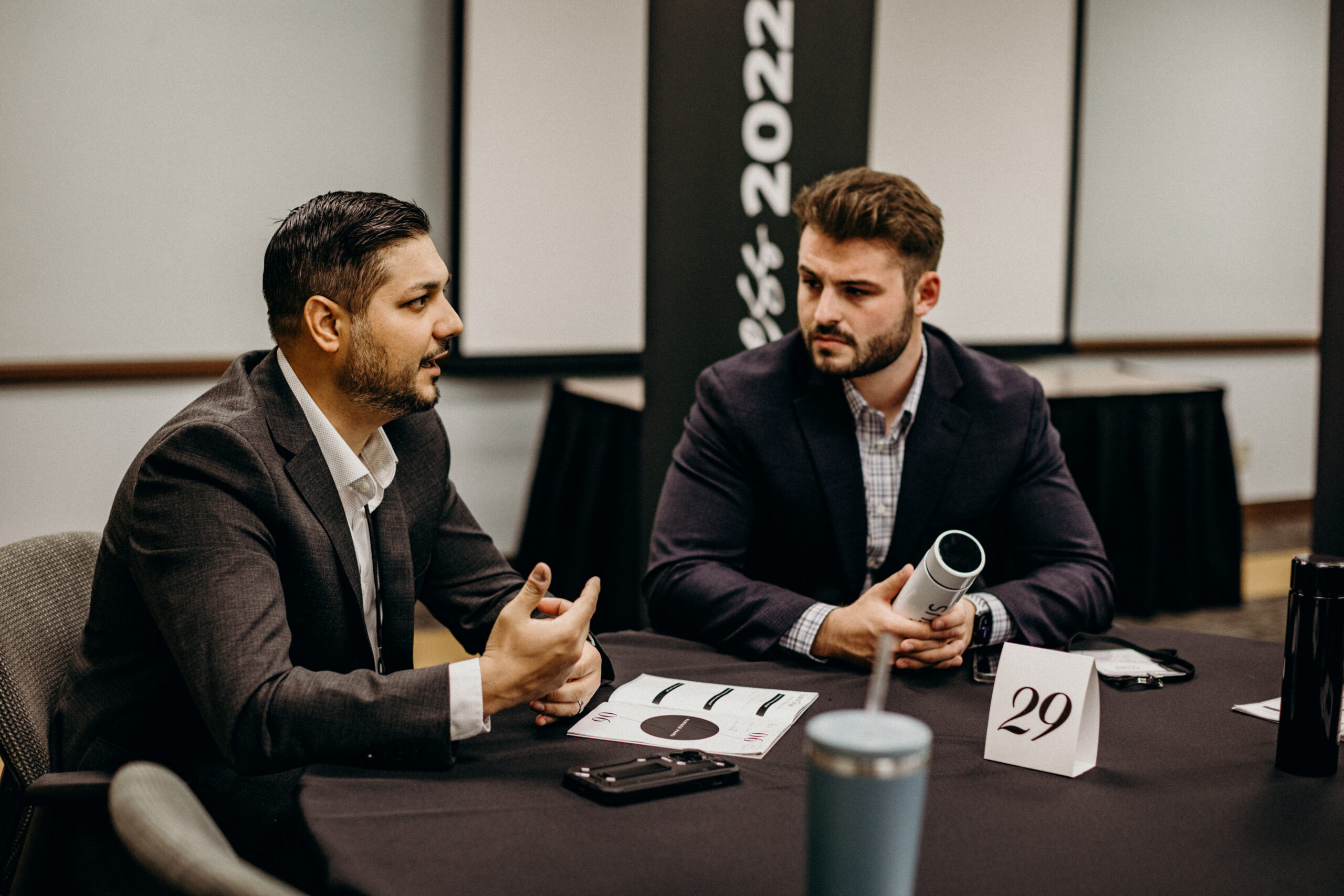 Two men speaking at a round table