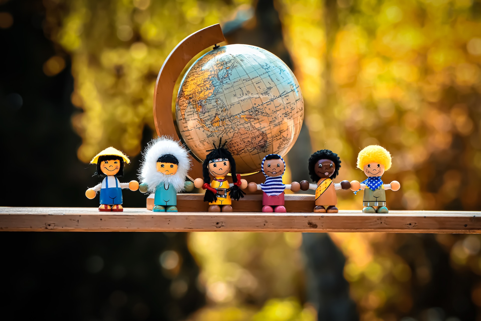 A diverse group of toys resembling children in front of a globe