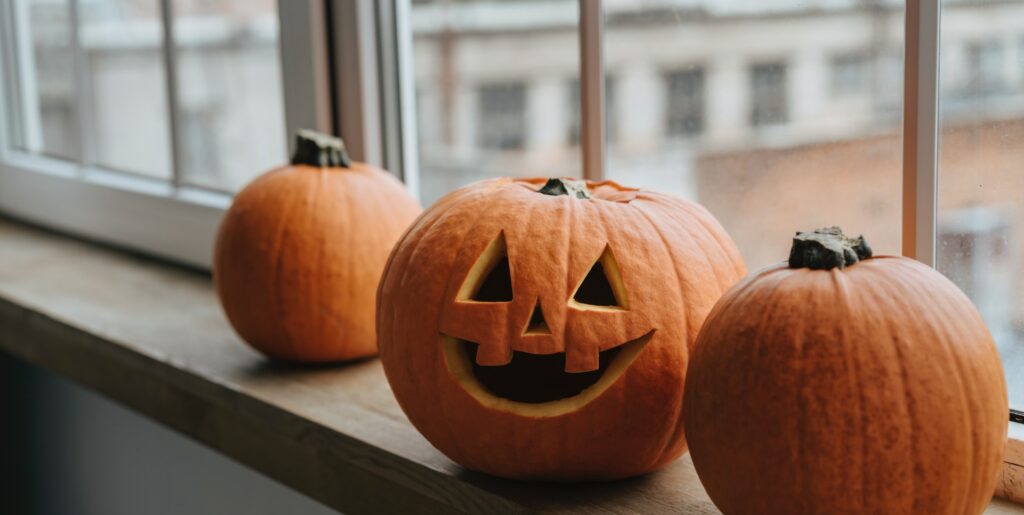 Three carved pumpkins placed on a window ledge.
