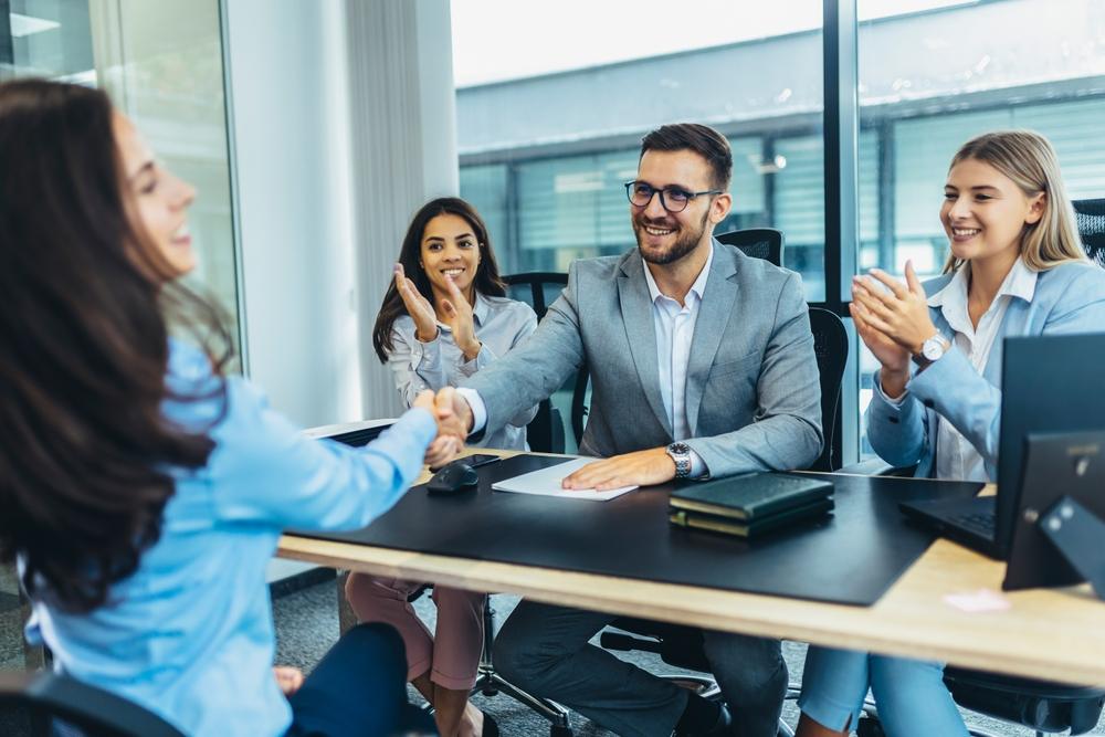 A hiring manager shaking hands with an interviewee during an interview.